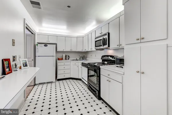 a kitchen with a refrigerator a sink and white cabinets