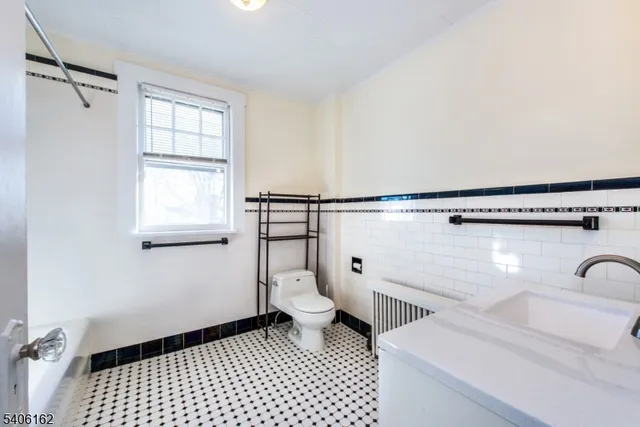 a bathroom with a sink a toilet a window and a mirror