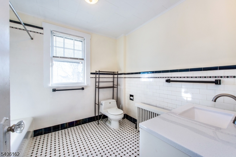 39 Baldwin Place, Unit 2 Bloomfield, NJ 07003 - Photo 11 of 17 a bathroom with a sink a toilet a window and a mirror
