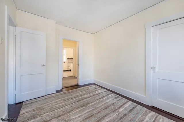 a view of an empty room with wooden floor and closet