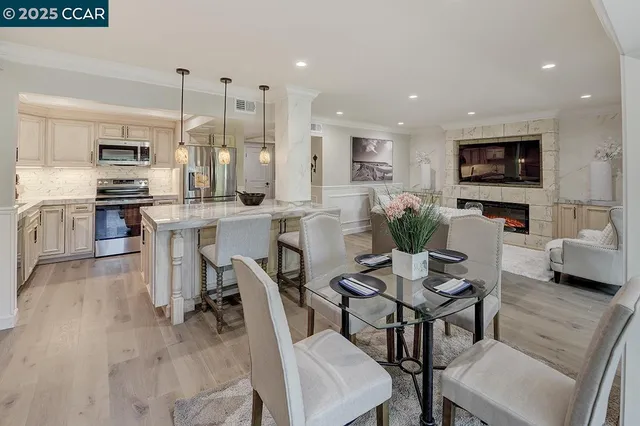 a view of kitchen with stainless steel appliances refrigerator stove dining table and chairs