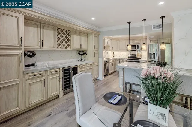 a kitchen with stainless steel appliances granite countertop a stove a sink a dining table and chairs with wooden floor