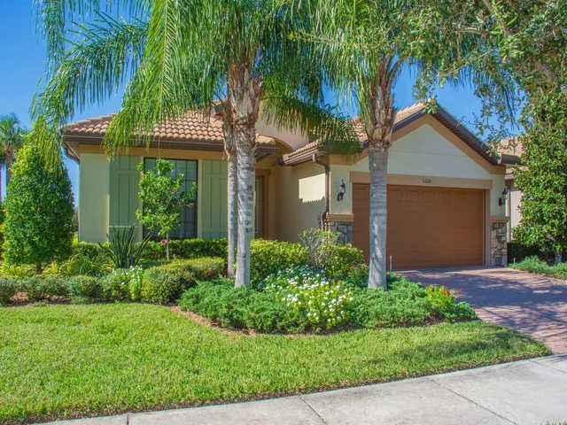 a view of a house with a yard and palm trees