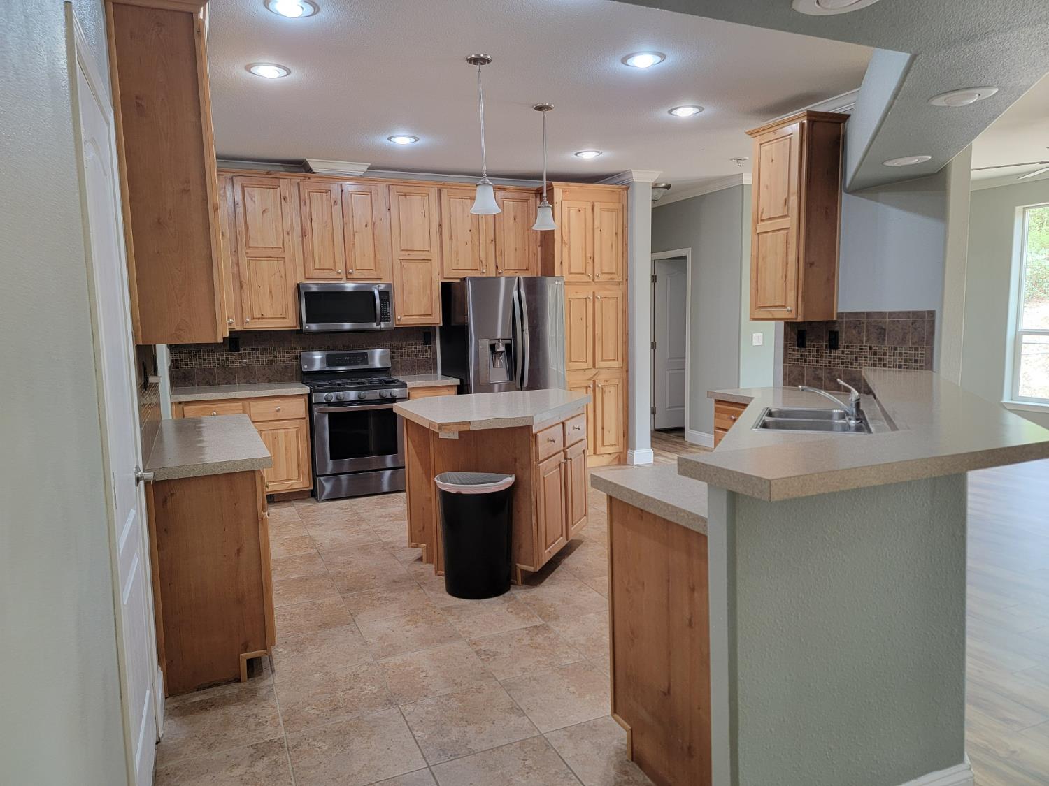 19327 American Flat Side Road Fiddletown, CA 95629 - Photo 9 of 25 Spacious kitchen featuring extensive hickory wood-finish cabinetry, black stainless steel appliances, a center island, and tile flooring