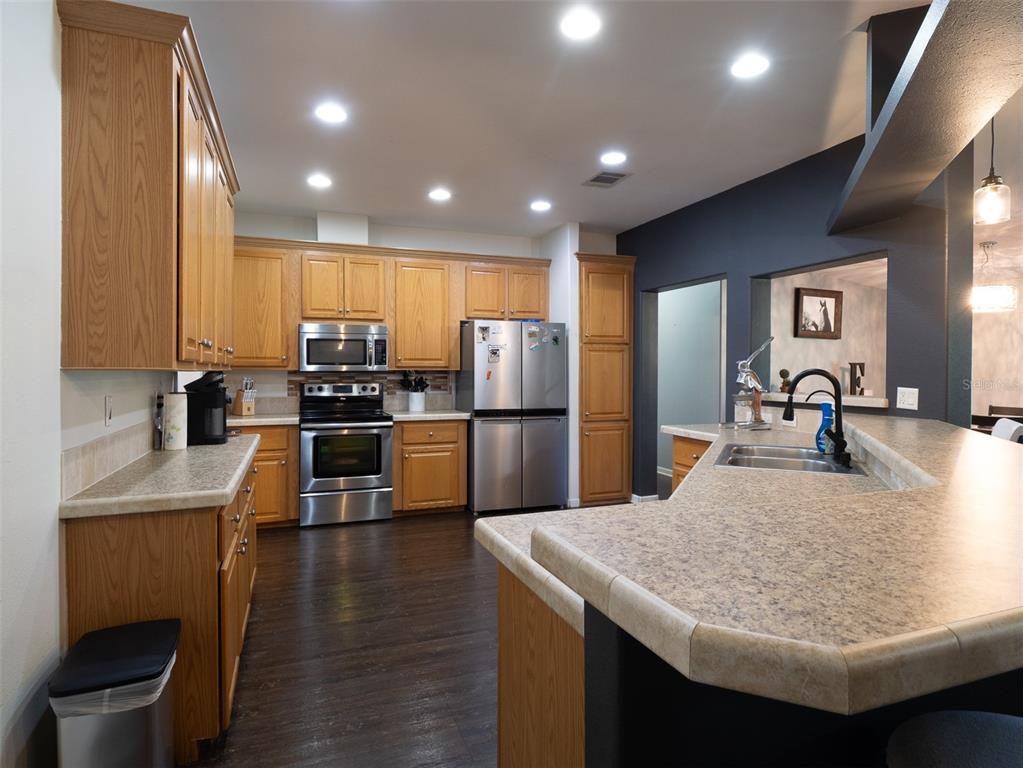 2900 Northwest 68th Avenue Ocala, FL 34482 - Photo 6 of 27 a kitchen with kitchen island stainless steel appliances a sink a stove a refrigerator cabinets and chairs