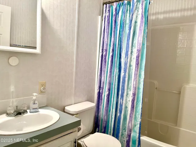 a bathroom with a sink a toilet a mirror and shower curtain