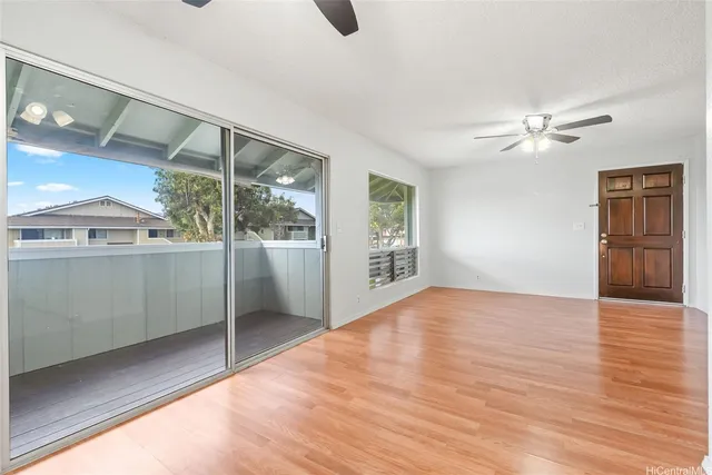 a view of an empty room with window and wooden floor