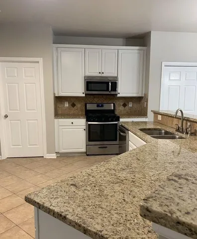 a kitchen with stainless steel appliances granite countertop a stove a sink and a microwave