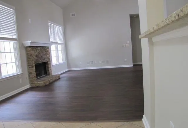 an empty room with wooden floor fireplace and windows