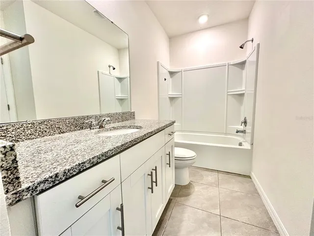 a bathroom with a granite countertop sink a toilet and a bathtub