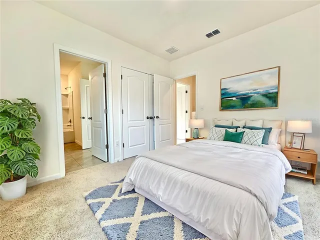 a spacious bedroom with a bed and a potted plant