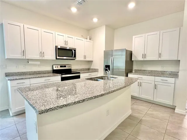 a kitchen with granite countertop a sink stainless steel appliances and white cabinets