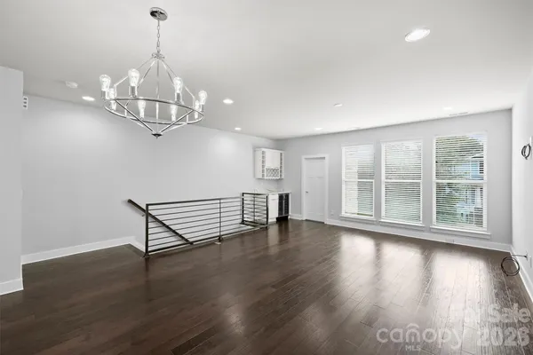 a view of a room with wooden floor chandelier and windows