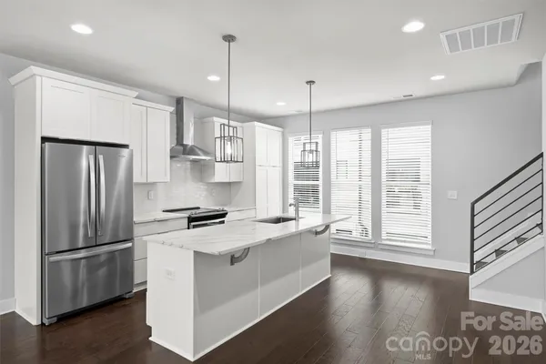 a kitchen with stainless steel appliances granite countertop a refrigerator a stove and a wooden floors
