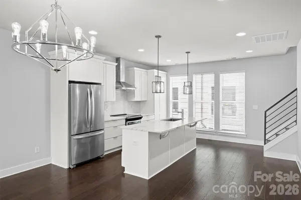 a kitchen with stainless steel appliances a refrigerator a sink dishwasher a stove and white cabinets with wooden floor