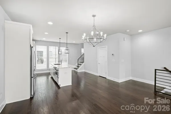 a view of a room with wooden floor chandelier and windows
