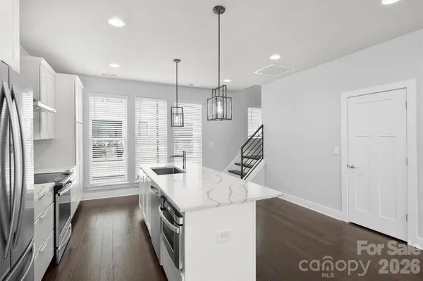 a kitchen with a sink a counter top space stainless steel appliances and a chandelier