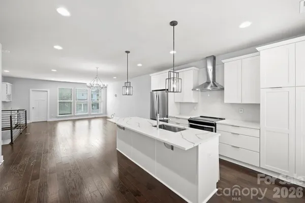 a kitchen with stainless steel appliances granite countertop a stove a sink a refrigerator a center island with wooden floor and cabinets