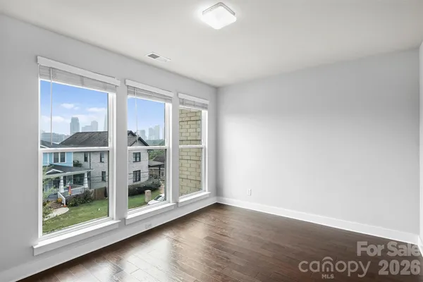an empty room with wooden floor and windows