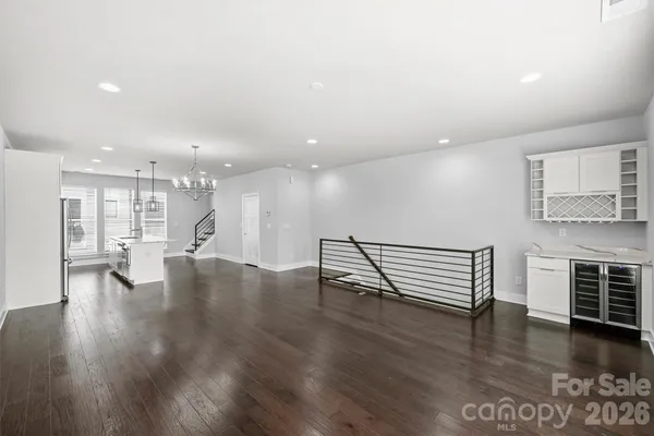 an empty room with wooden floor and kitchen view