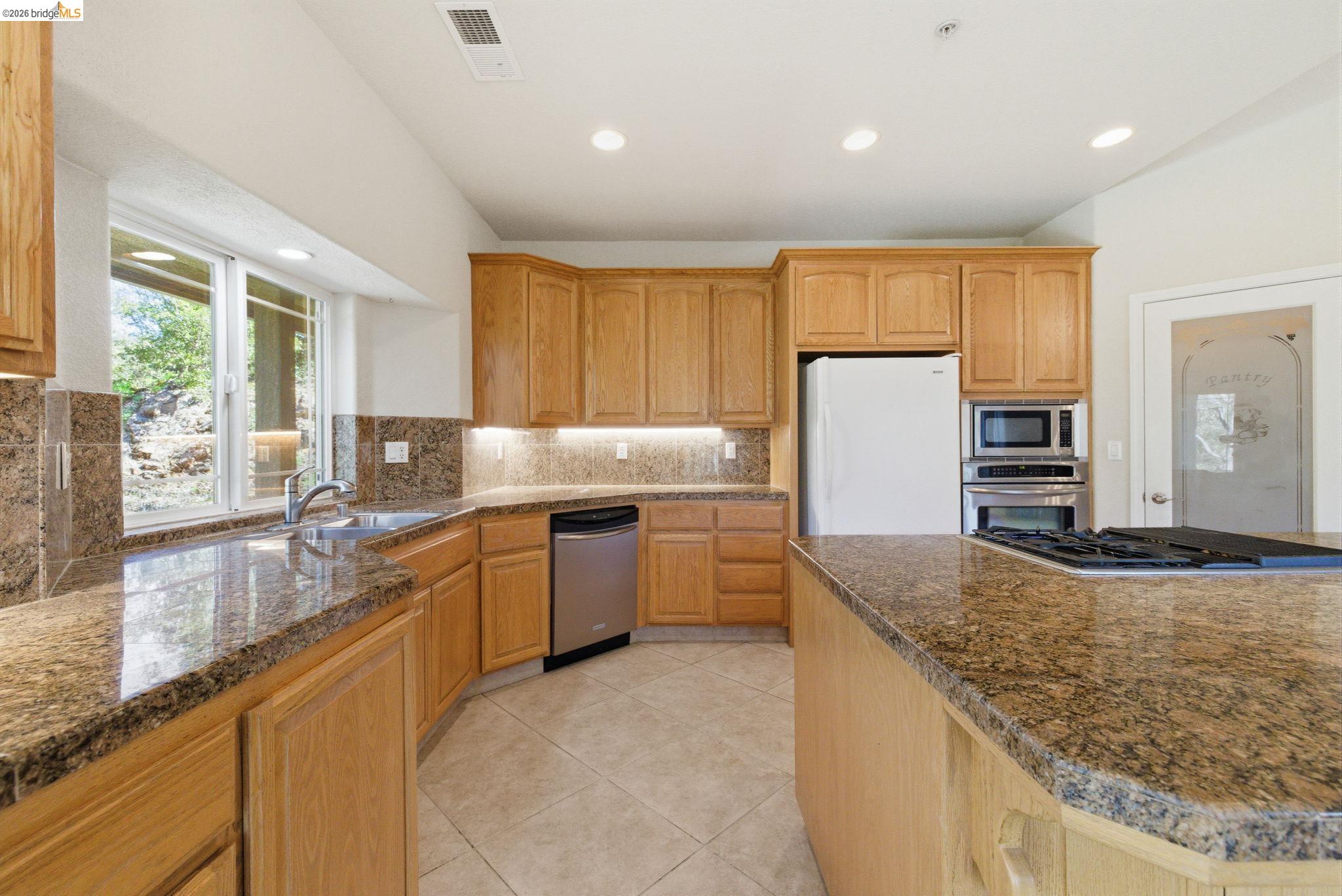 20245 Tuolumne Road North Tuolumne, CA 95379 - Photo 16 of 43 a kitchen with granite countertop a sink a counter top space appliances and cabinets