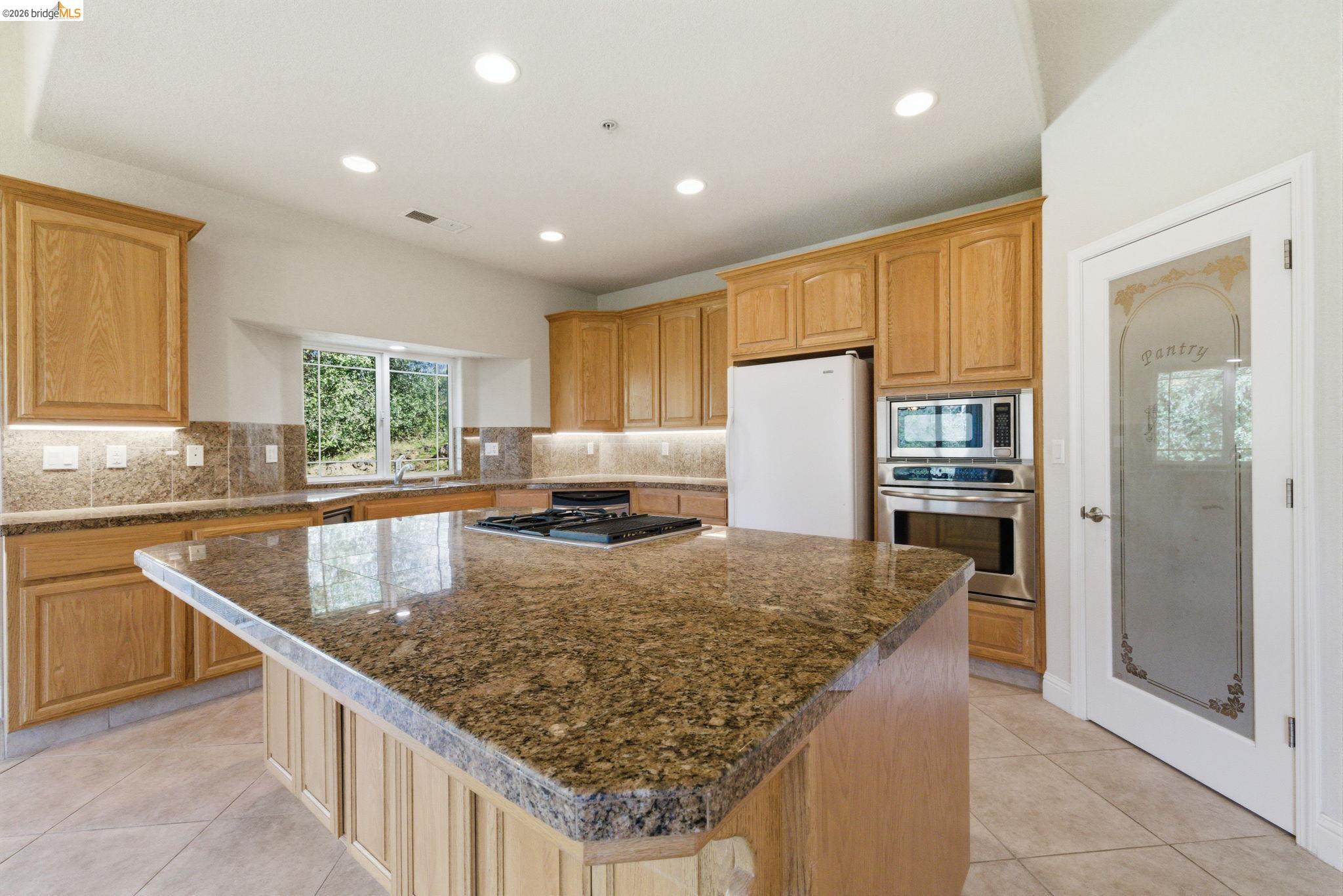 20245 Tuolumne Road North Tuolumne, CA 95379 - Photo 17 of 43 a kitchen with kitchen island granite countertop wooden cabinets a refrigerator and a sink