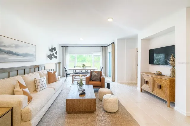 a living room with furniture flat screen tv and large windows