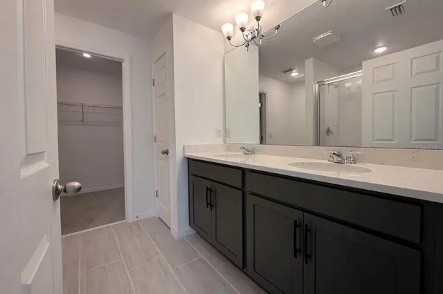 a bathroom with a double vanity sink a large mirror and shower