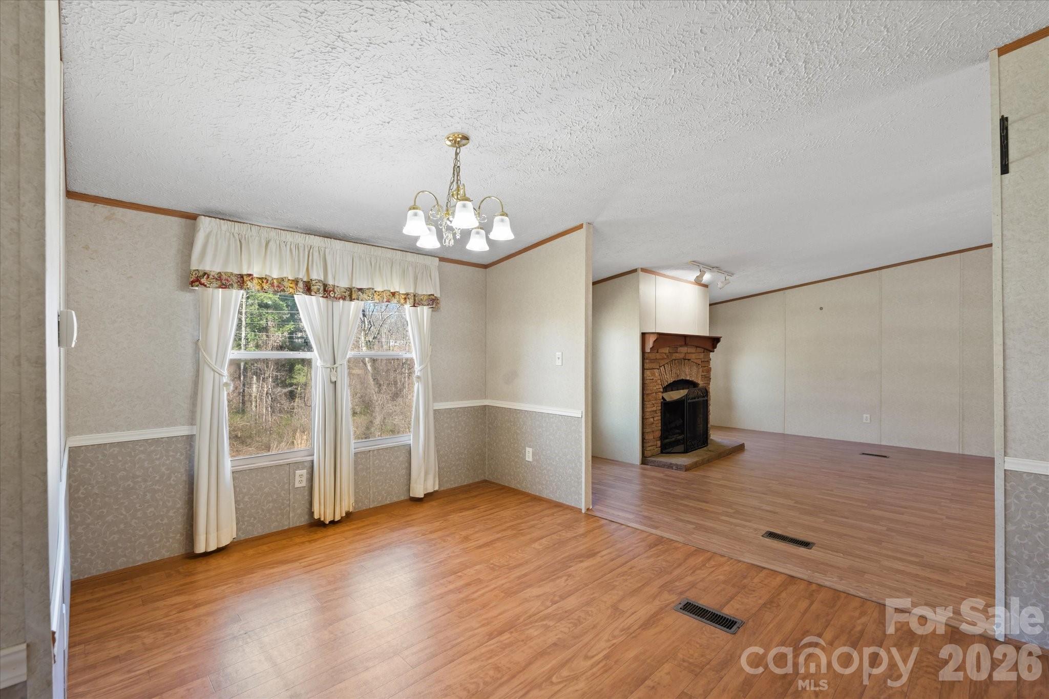 18 Ford Valley Road Weaverville, NC 28787 - Photo 10 of 37 an empty room with wooden floor fireplace and chandelier