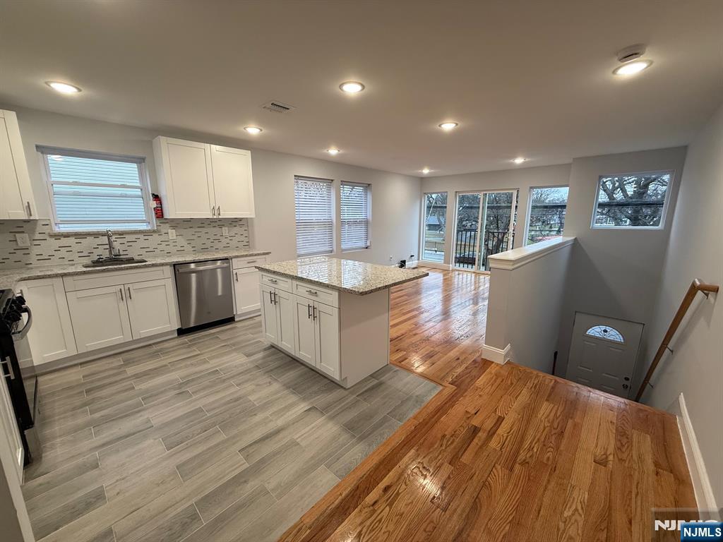 a living room with stainless steel appliances granite countertop furniture wooden floor and a sink
