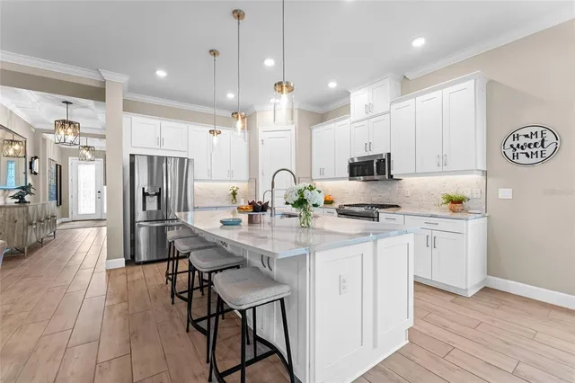 a kitchen with stainless steel appliances kitchen island granite countertop a sink refrigerator and cabinets