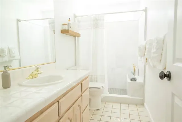 a bathroom with a granite countertop sink a toilet and shower