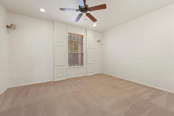 an empty room with chandelier fan and windows