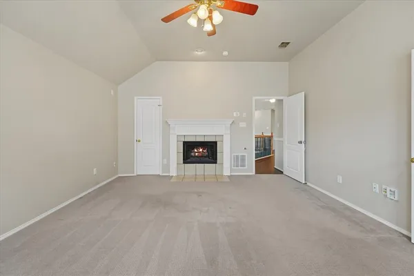 an empty room with a fireplace and chandelier fan