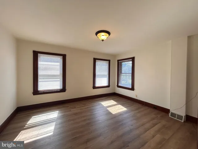 a view of an empty room with glass door and wooden floor