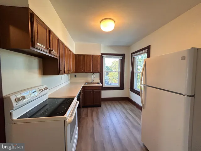 a kitchen with a refrigerator a stove a sink dishwasher and wooden cabinets with wooden floor