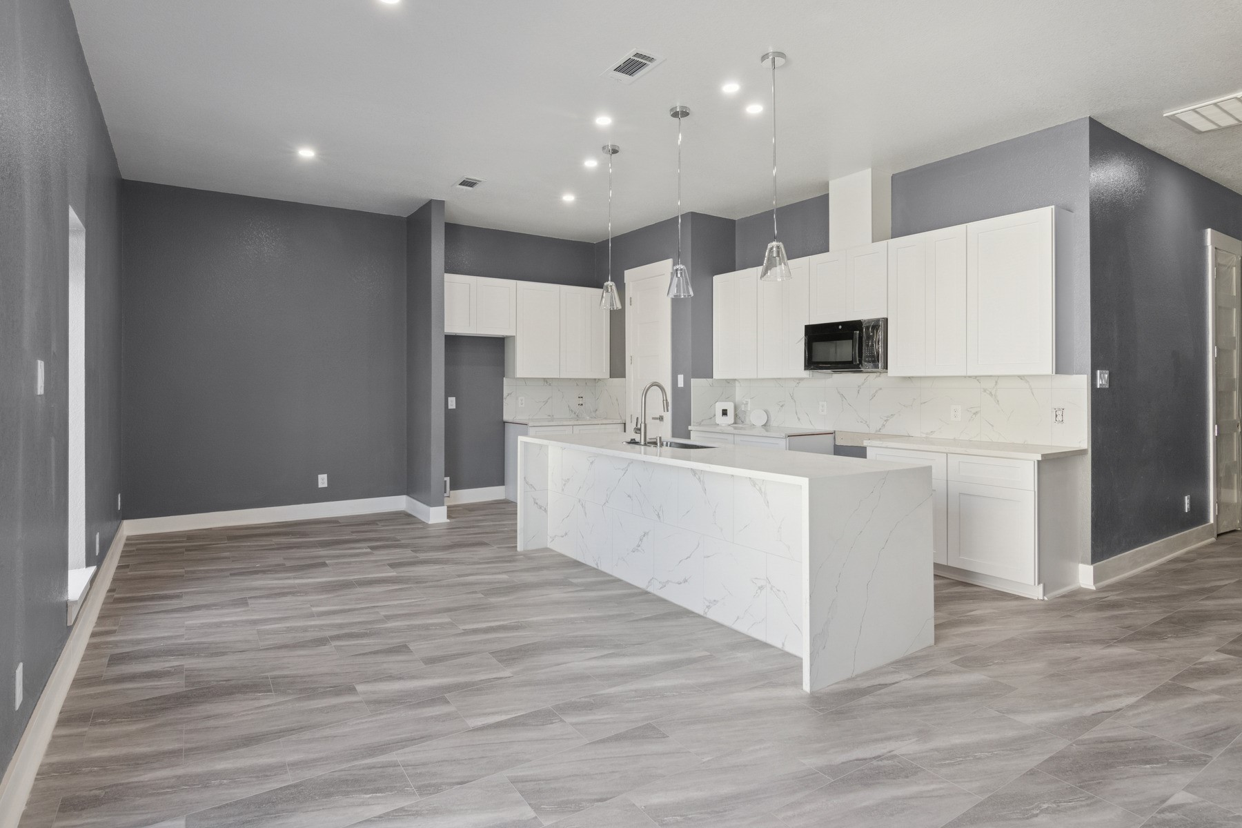 4704 Ward Street Houston, TX 77021 - Photo 9 of 20 a large white kitchen with kitchen island a sink dishwasher a stove a refrigerator and white cabinets with wooden floor