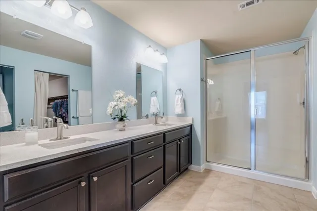 a bathroom with a double vanity sink mirror and shower