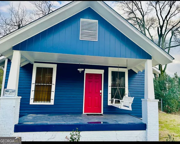 a view of wooden house with a small yard and large tree