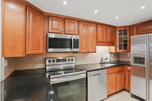 a kitchen with stainless steel appliances granite countertop a stove a sink and a microwave