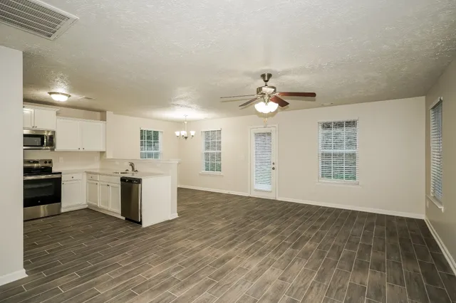 a view of an empty room with kitchen and a window