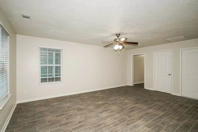 a view of an empty room with wooden floor and a window