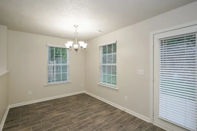 an empty room with wooden floor chandelier and windows
