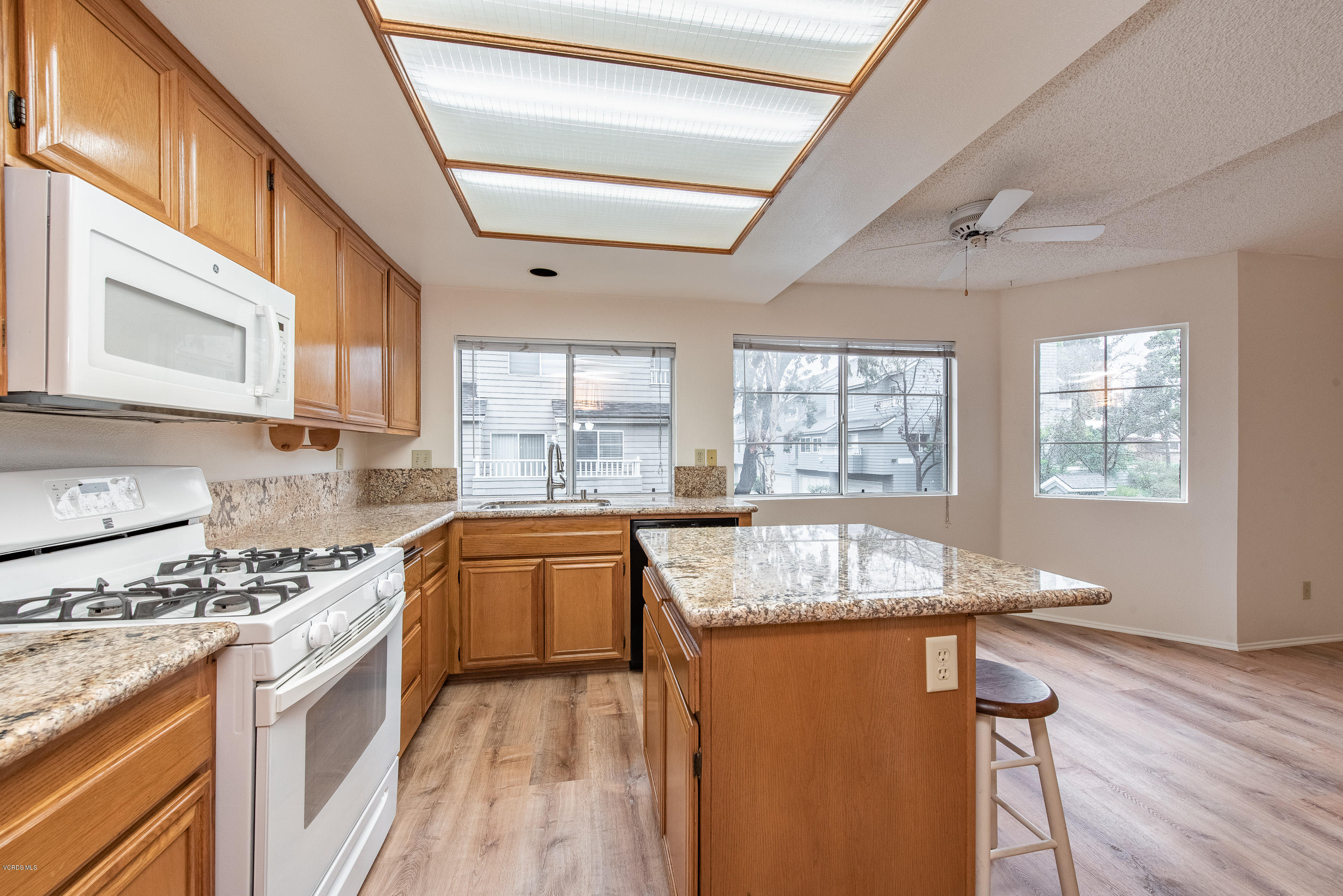 4975 Telephone Road Ventura, CA 93003 - Photo 12 of 31 a kitchen with granite countertop wooden cabinets a stove a sink and a large window
