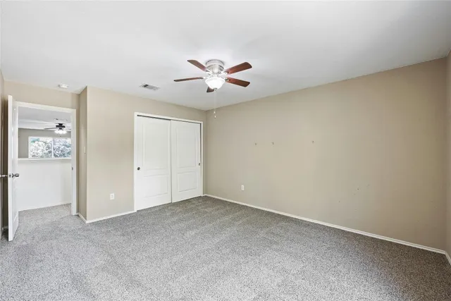 an empty room with closet and a ceiling fan