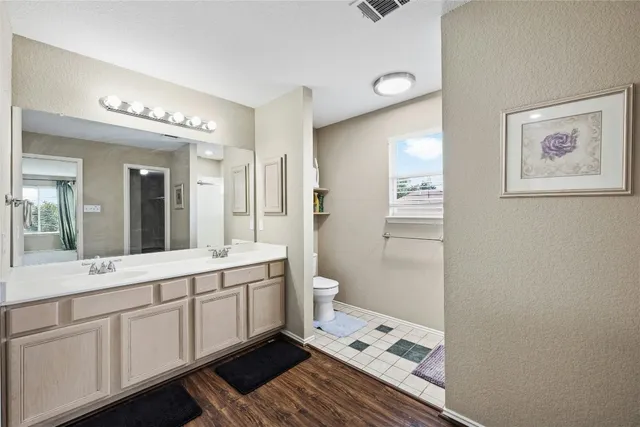 a spacious bathroom with a double vanity sink a toilet and a mirror