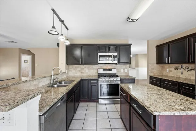 a kitchen with stainless steel appliances granite countertop a stove a sink and a microwave