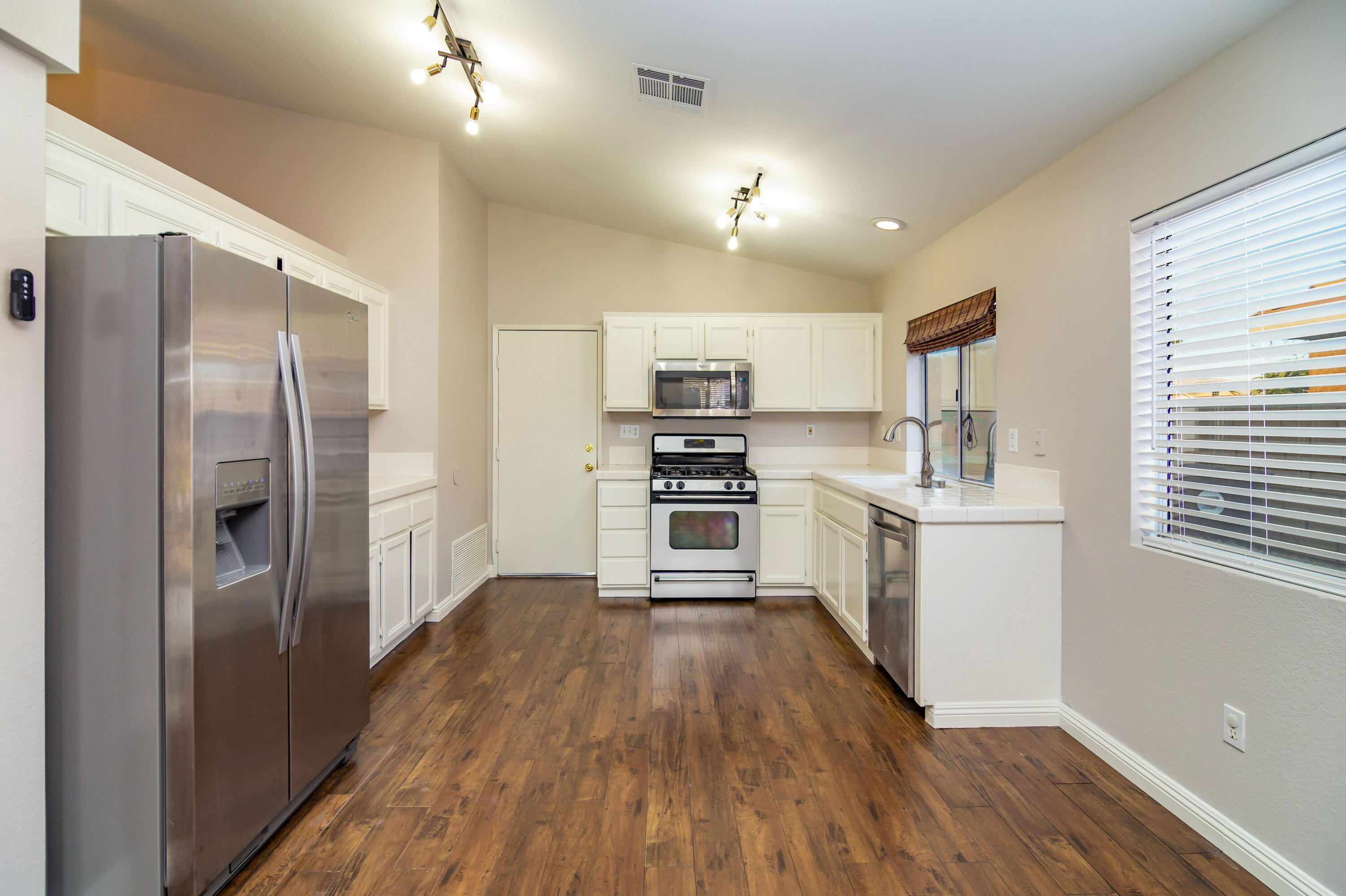 80265 Moonshadow Drive Indio, CA 92201 - Photo 20 of 32 a kitchen with stainless steel appliances a refrigerator a sink cabinets and wooden floor