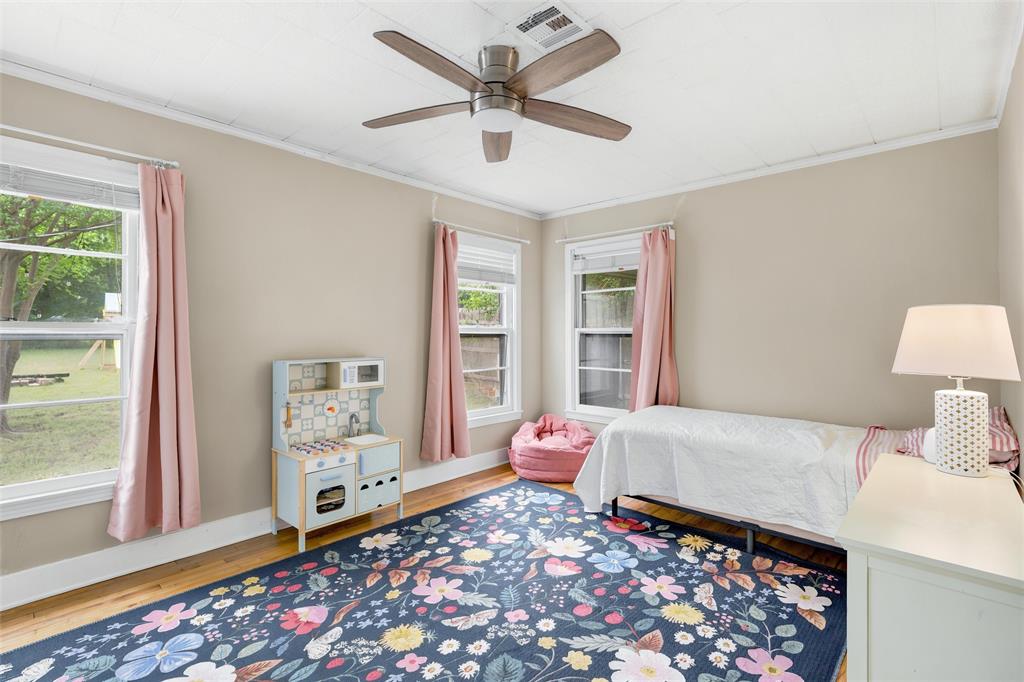 3012 Mitchell Avenue Waco, TX 76708 - Photo 10 of 18 Room featuring wood-finish flooring, two windows with white trim, and a ceiling fan with integrated lighting