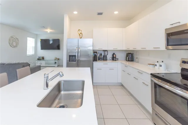 a large white kitchen with stainless steel appliances granite countertop a sink and white cabinets